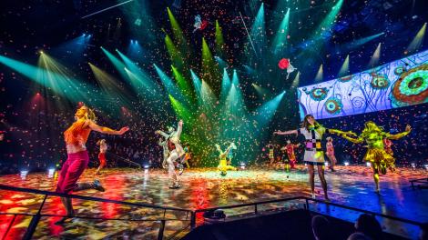 Dans une explosion de joie communicative, des acrobates évoluent sur des cordes tandis que toute la troupe d’artistes et les spectateurs sont gagnés par l’euphorie suscitée par la « Beatlemania ». Dans une explosion de joie communicative, des acrobates évoluent sur des cordes tandis que toute la troupe d’artistes et les spectateurs sont gagnés par l’euphorie suscitée par la « Beatlemania ».