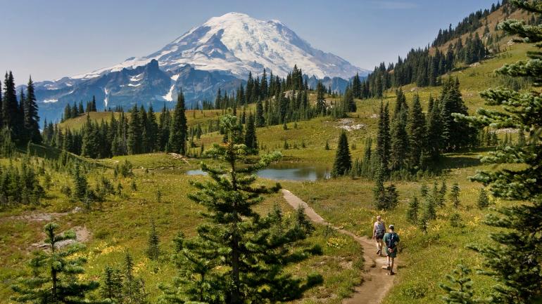Hikers along a trail in the shadow of Mount Rainier in Washington Hikers along a trail in the shadow of Mount Rainier in Washington
