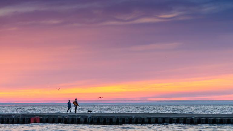 Couple walking along a pier at sunset in Grand Haven, Michigan Couple walking along a pier at sunset in Grand Haven, Michigan