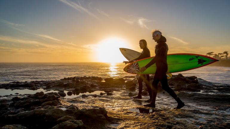 Two surfers walking with surfboards at sunset in Santa Cruza, California Two surfers walking with surfboards at sunset in Santa Cruza, California