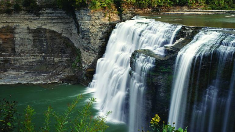 Water tumbles over a cliff surrounded by lush scenery at Letchworth State Park. Water tumbles over a cliff surrounded by lush scenery at Letchworth State Park.