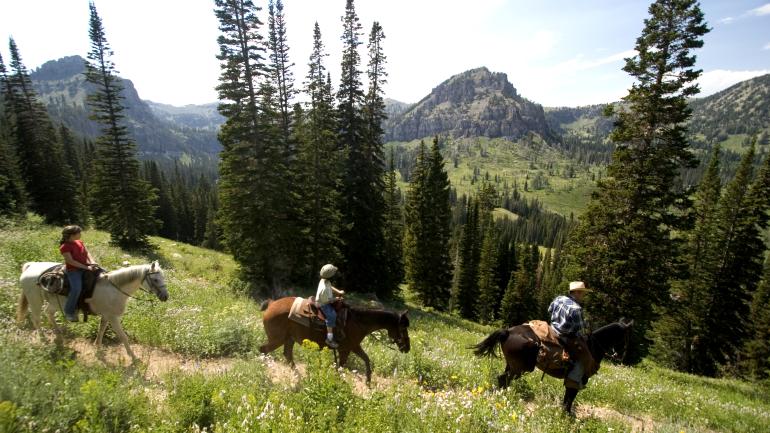 Children and adult horseback riding on rugged trail overlooking scenic mountain vista in the Cache Valley of Utah. Children and adult horseback riding on rugged trail overlooking scenic mountain vista in the Cache Valley of Utah.