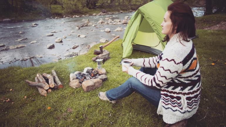 A camper resting by a stream strewn with rocks A camper resting by a stream strewn with rocks