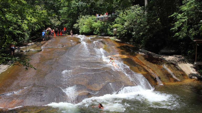 Swimmers sliding down the smooth-surfaced Sliding Rock boulder in Pisgah National Forest Swimmers sliding down the smooth-surfaced Sliding Rock boulder in Pisgah National Forest