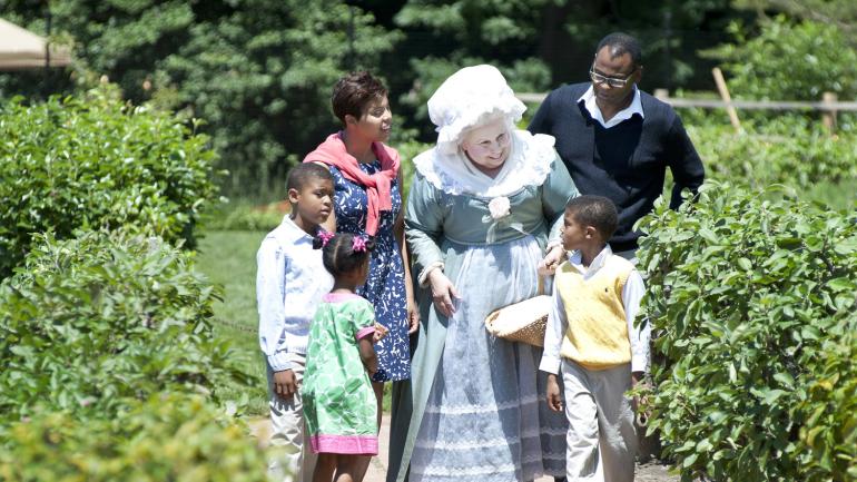 A Martha Washington reenactor interacting with a family in the estate’s extensive gardens A Martha Washington reenactor interacting with a family in the estate’s extensive gardens