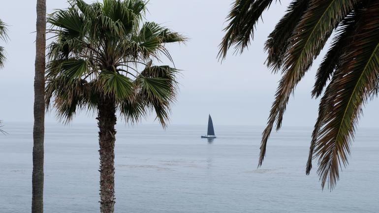 A sailboat cruises along the California coast. A sailboat cruises along the California coast.