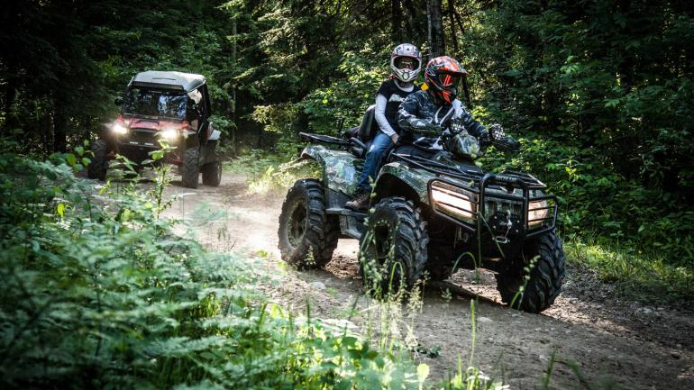 Riding ATVs through a forest trail in Grand Rapids Riding ATVs through a forest trail in Grand Rapids