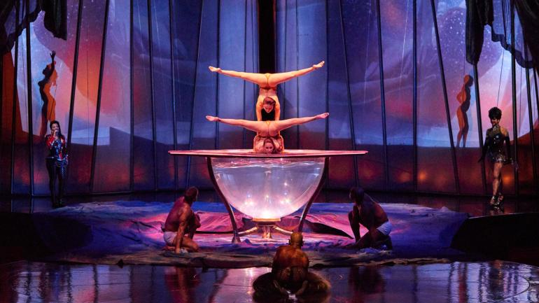 Two contortionists perform a balancing act, testing innocence and inhibitions. Two contortionists perform a balancing act, testing innocence and inhibitions.