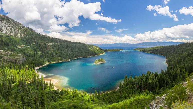 An alpine forest surrounds the aquamarine waters of Lake Tahoe An alpine forest surrounds the aquamarine waters of Lake Tahoe