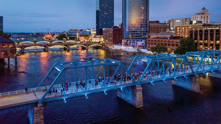 Das Zentrum von Grand Rapids und der Fußgängerweg der Blue Bridge über den Grand River aus der Vogelperspektive Das Zentrum von Grand Rapids und der Fußgängerweg der Blue Bridge über den Grand River aus der Vogelperspektive