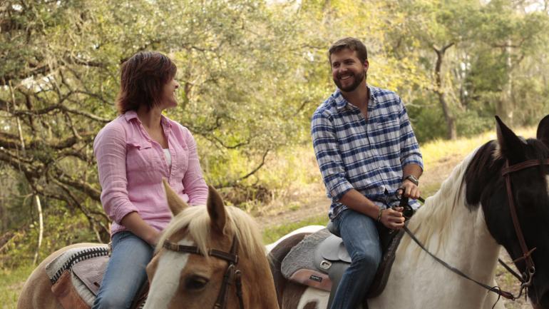 Casal curtindo os ambientes ao ar livre a cavalo em um passeio pela trilha Casal curtindo os ambientes ao ar livre a cavalo em um passeio pela trilha