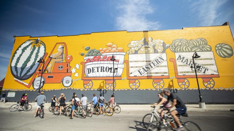 Kurzer Stopp während einer Radtour durch Detroit, um ein Wandgemälde am Eastern Market District zu betrachten Kurzer Stopp während einer Radtour durch Detroit, um ein Wandgemälde am Eastern Market District zu betrachten