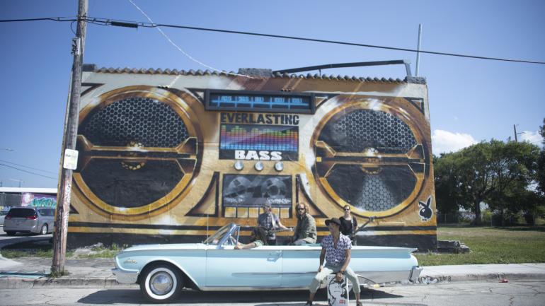 The band posing with a music-themed Miami mural The band posing with a music-themed Miami mural