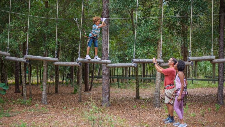 Navigating a set of swinging logs at Orlando Tree Trek Adventure Park Navigating a set of swinging logs at Orlando Tree Trek Adventure Park