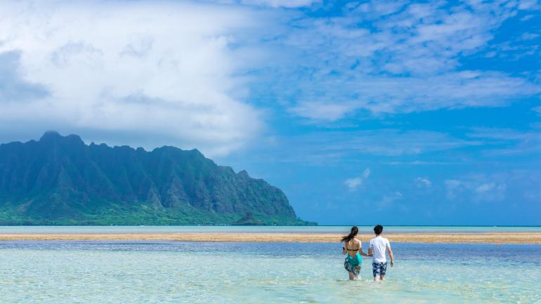Couple wading in the serene, crystal-clear waters of Kaneohe Bay Couple wading in the serene, crystal-clear waters of Kaneohe Bay