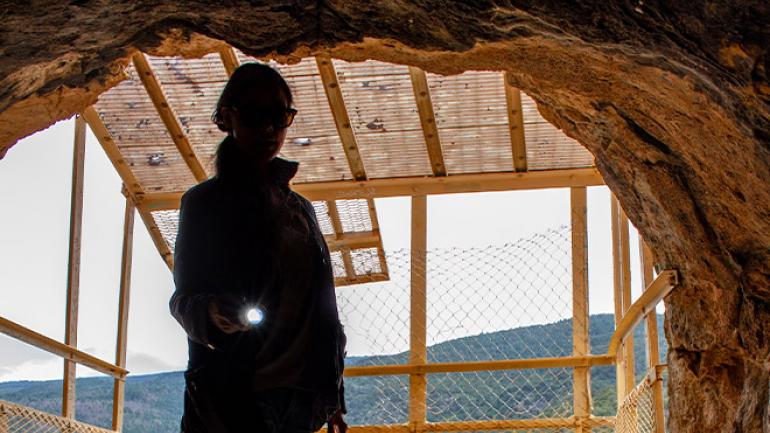Peering into Sandia Man Cave framed by views of the Cibola National Forest and National Grasslands Peering into Sandia Man Cave framed by views of the Cibola National Forest and National Grasslands