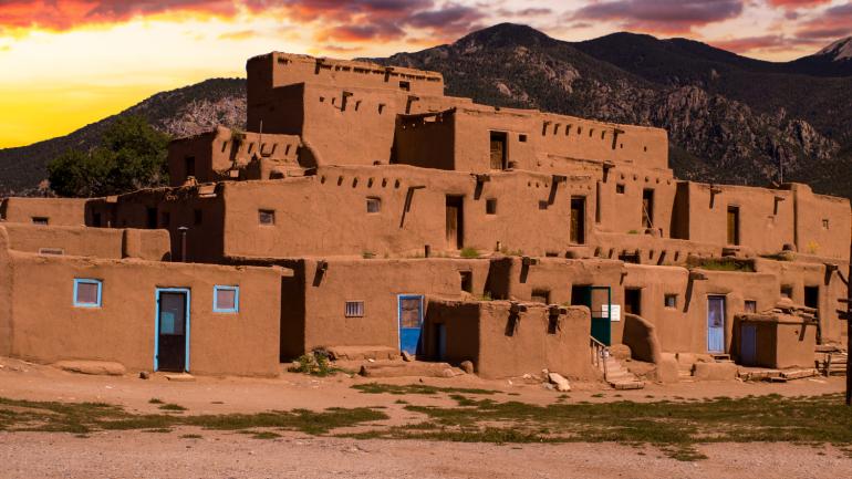 Coucher de soleil sur Taos Pueblo avec les monts Sangre de Cristo à l’arrière-plan Coucher de soleil sur Taos Pueblo avec les monts Sangre de Cristo à l’arrière-plan