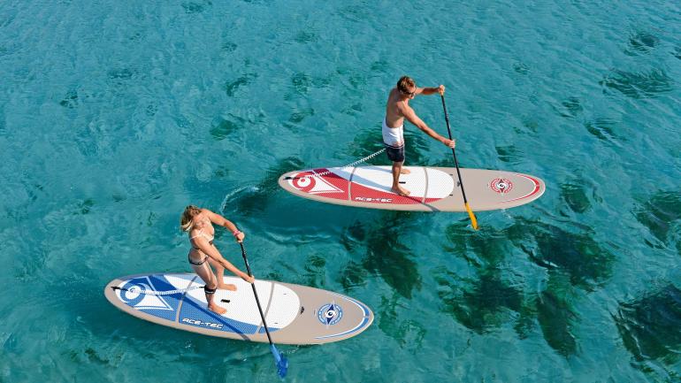 Couple faisant du paddle sur les eaux cristallines du littoral Couple faisant du paddle sur les eaux cristallines du littoral