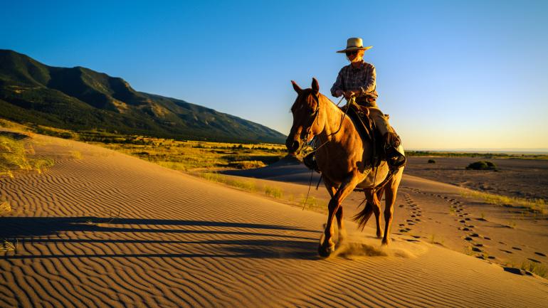 Horseback riding across sand dunes at Zapata Ranch Horseback riding across sand dunes at Zapata Ranch