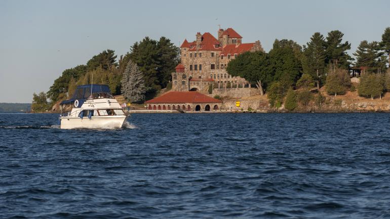 A boat passing Singer Castle in the Thousand Islands in New York State A boat passing Singer Castle in the Thousand Islands in New York State