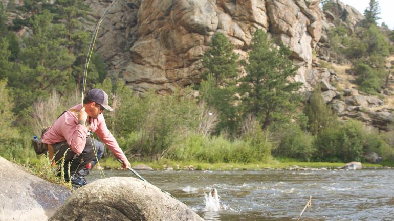Reeling in a catch while fishing on the North Platte River Reeling in a catch while fishing on the North Platte River