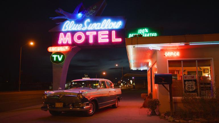 A vintage car and neon sign with the words illuminated outside the Blue Swallow Motel in Tucumcari, New Mexico A vintage car and neon sign with the words illuminated outside the Blue Swallow Motel in Tucumcari, New Mexico