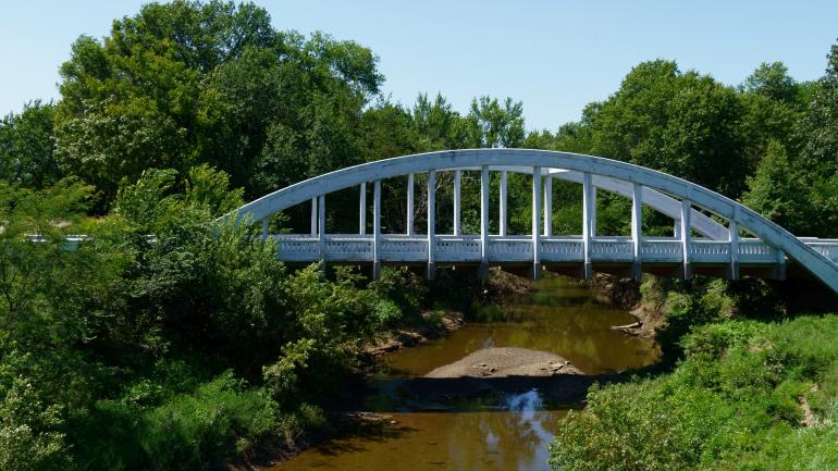 An arched “rainbow” bridge spans over Brush Creek in Riverton, Kansas An arched “rainbow” bridge spans over Brush Creek in Riverton, Kansas