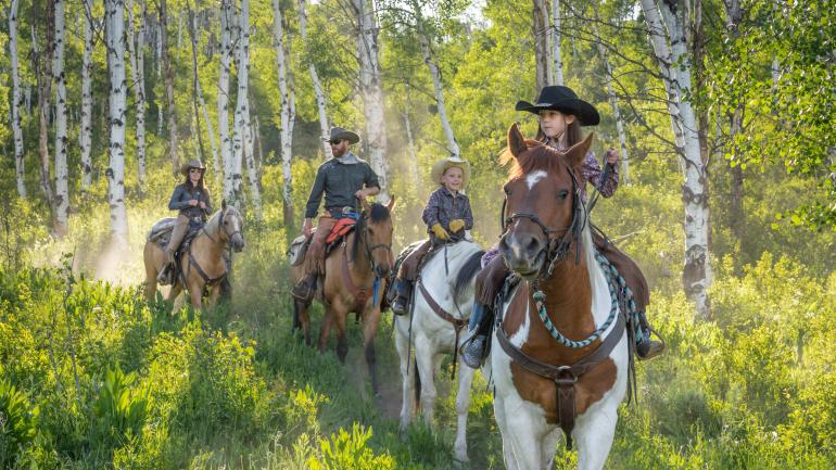 A family riding horses on a Colorado dude ranch trail A family riding horses on a Colorado dude ranch trail
