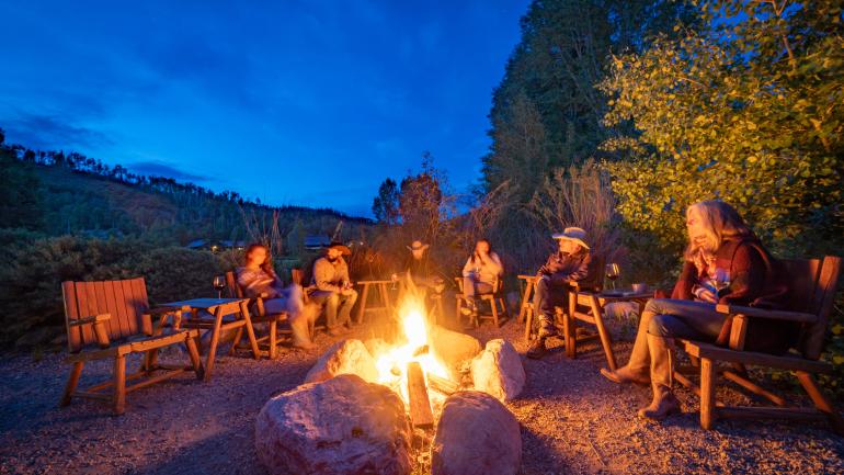 Dude ranch guests having evening drinks around a campfire Dude ranch guests having evening drinks around a campfire