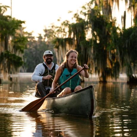 Couple canoeing alongside cypress trees on Lake Martin near Breaux Bridge, Louisiana
