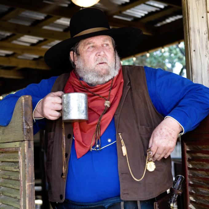 Vaquero con una bebida afuera de una cantina en Texas Vaquero con una bebida afuera de una cantina en Texas