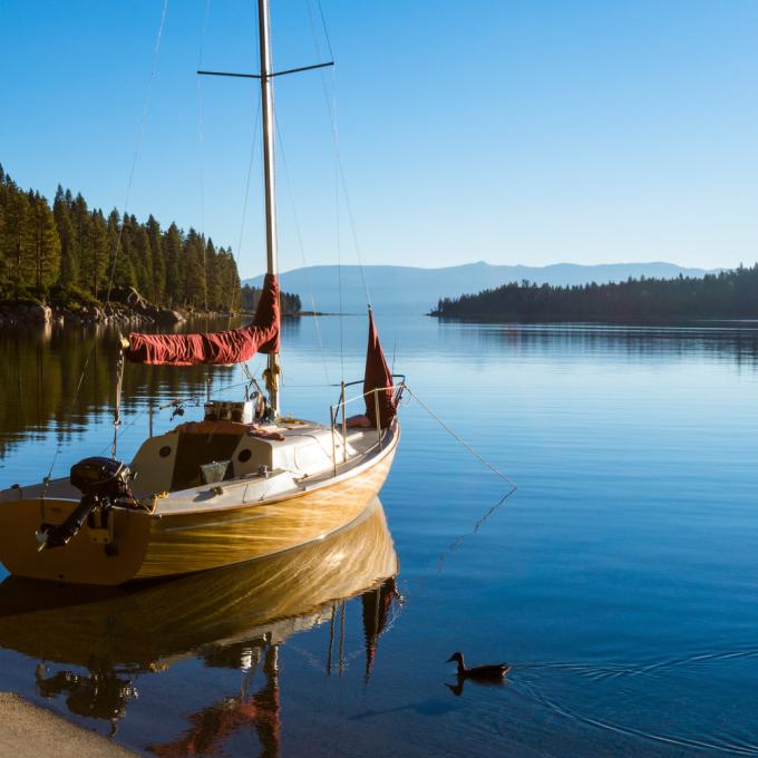 A lone sailboat waits at the edge of the lake A lone sailboat waits at the edge of the lake