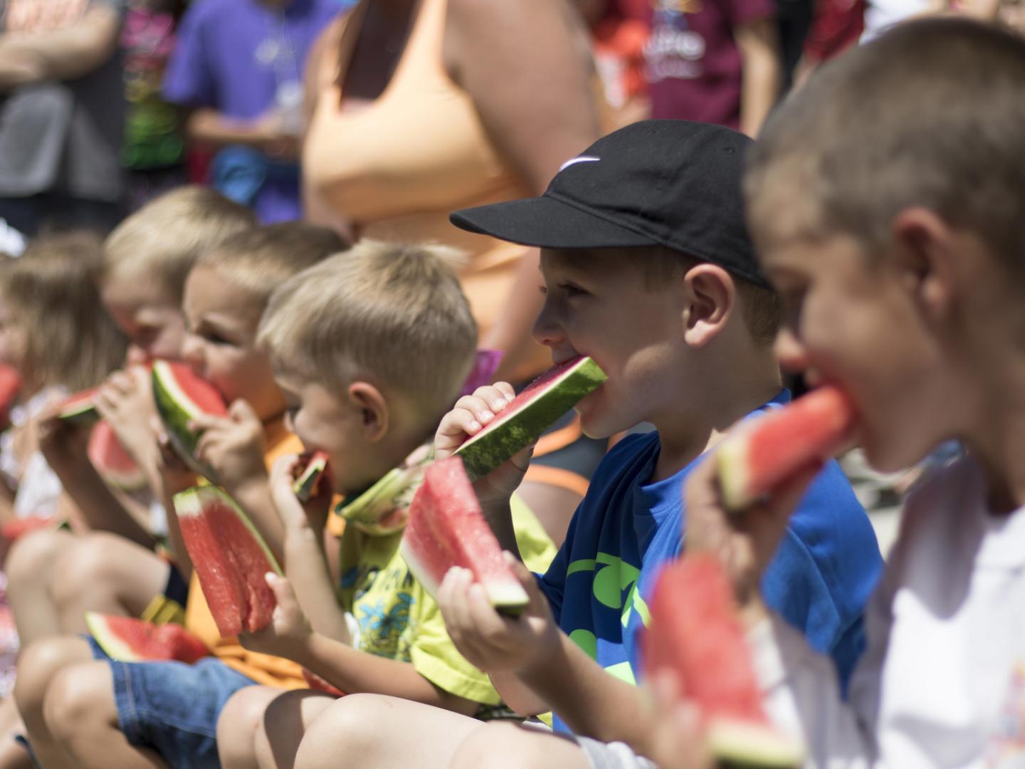 Une ligne de jeunes gastronomes croquant dans une pastèque pendant les Escalante Days Une ligne de jeunes gastronomes croquant dans une pastèque pendant les Escalante Days