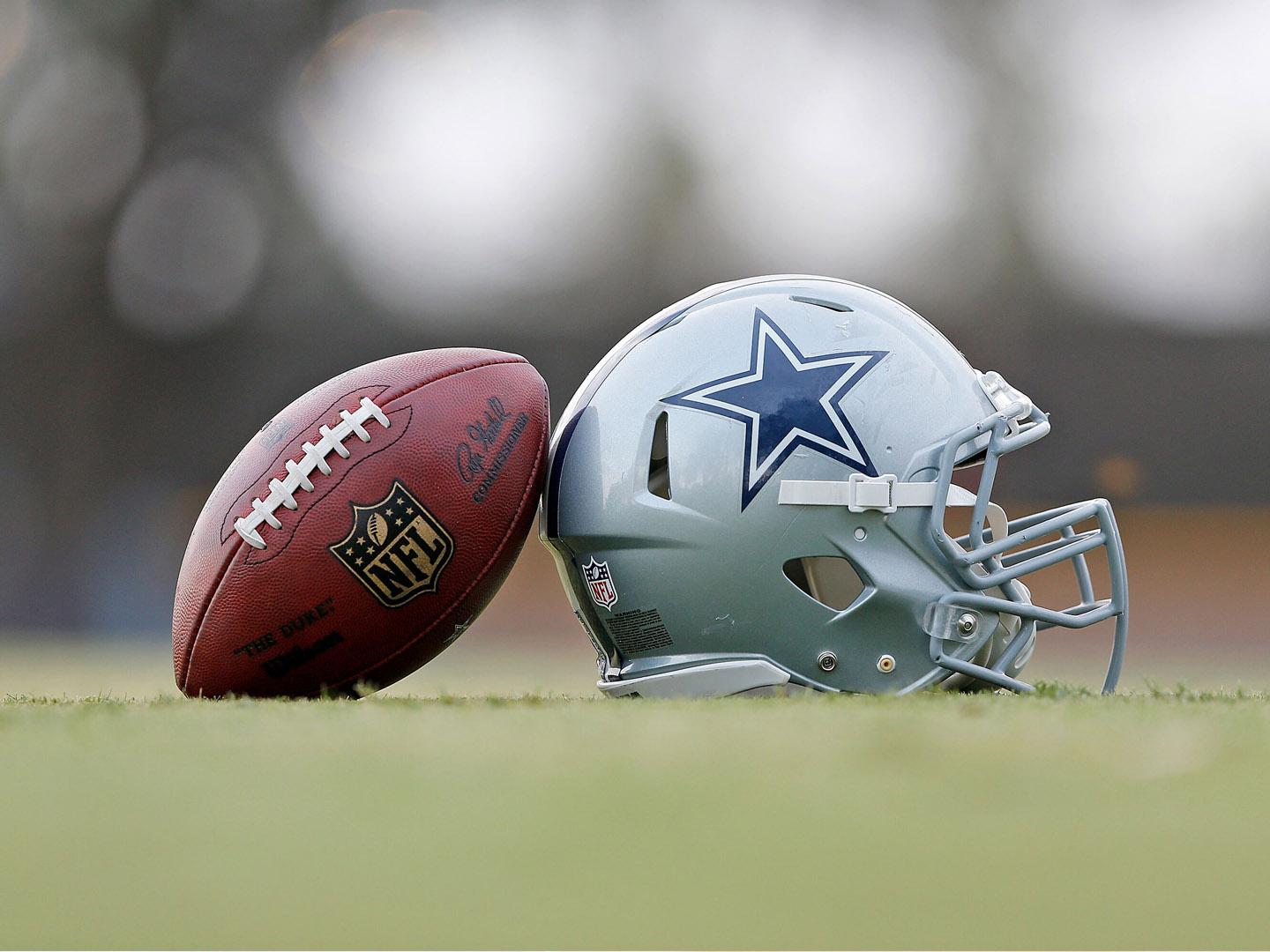 Ein Football und ein Helm mit dem Logo der Dallas Cowboys im Trainingszentrum in Oxnard, Kalifornien Ein Football und ein Helm mit dem Logo der Dallas Cowboys im Trainingszentrum in Oxnard, Kalifornien