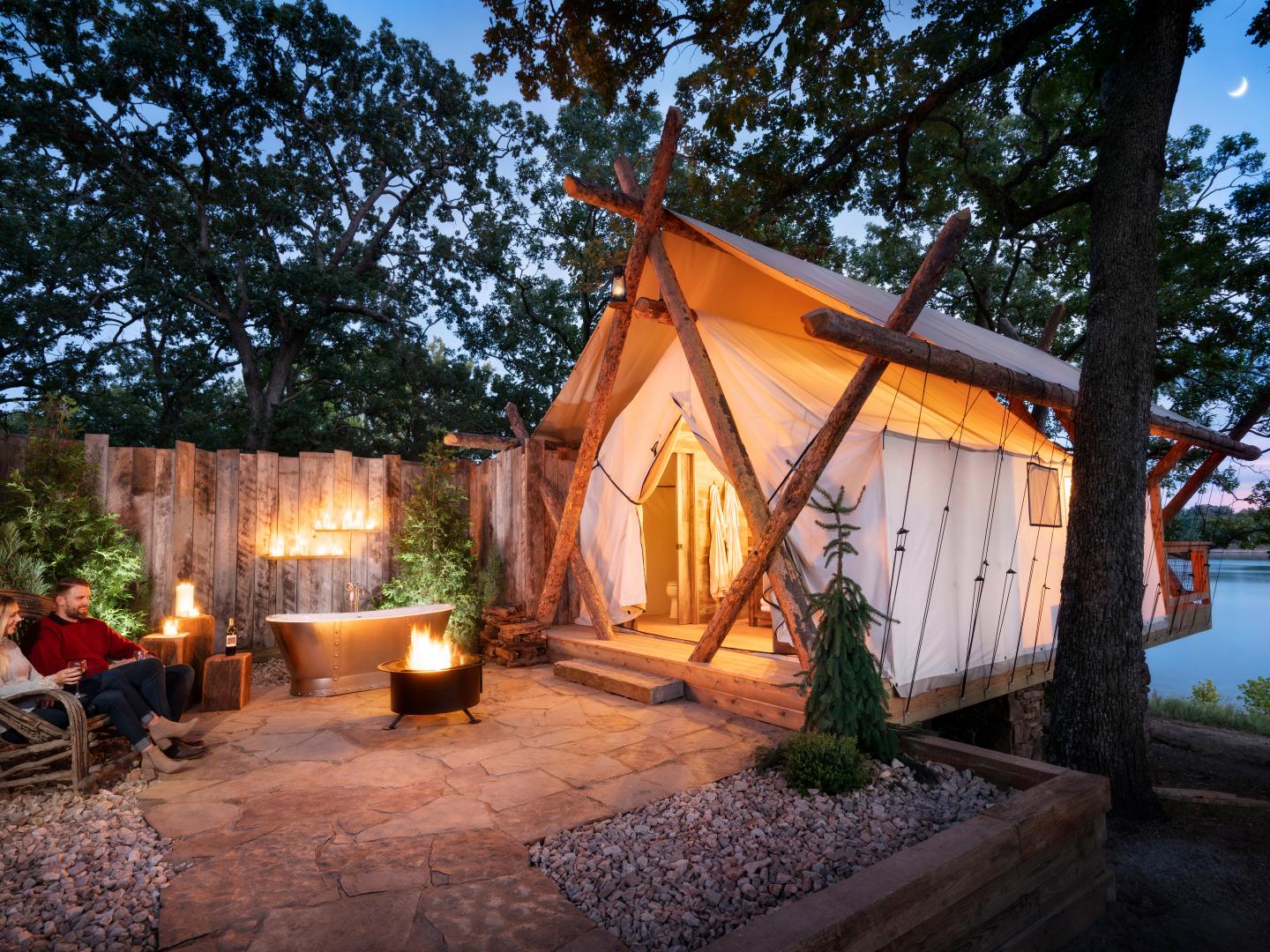 Couple relaxing by the fire and their glamping tent at Camp Long Creek at Big Cedar Lodge in Ridgedale, Missouri Couple relaxing by the fire and their glamping tent at Camp Long Creek at Big Cedar Lodge in Ridgedale, Missouri