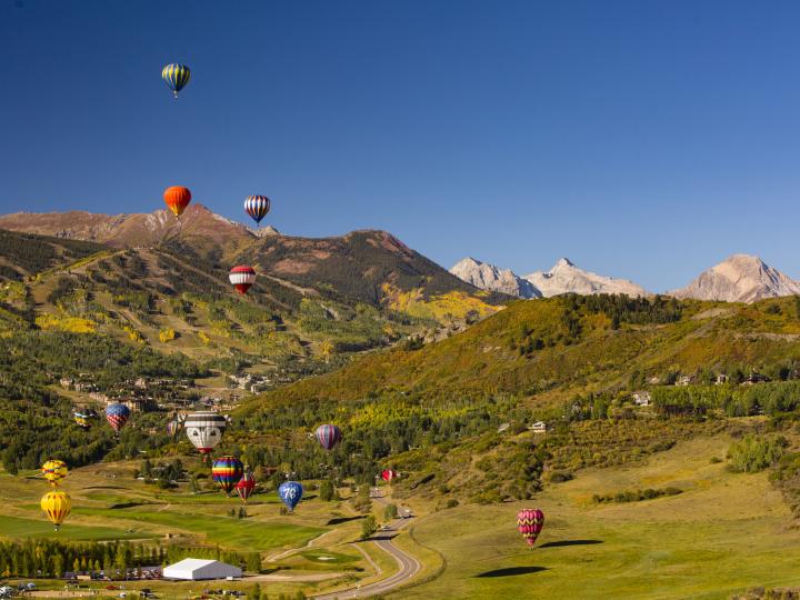 Hot air balloons floating over the landscape during the Snowmass Balloon Festival in Colorado