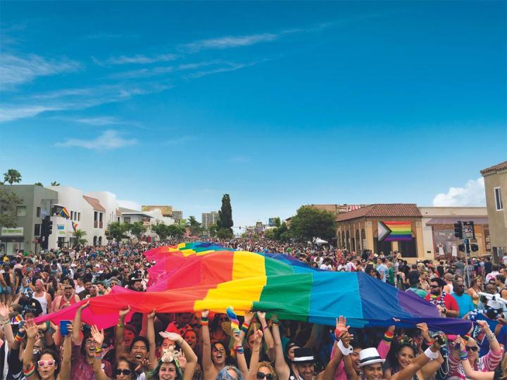 A crowd lifts a rainbow flag during San Diego Pride A crowd lifts a rainbow flag during San Diego Pride
