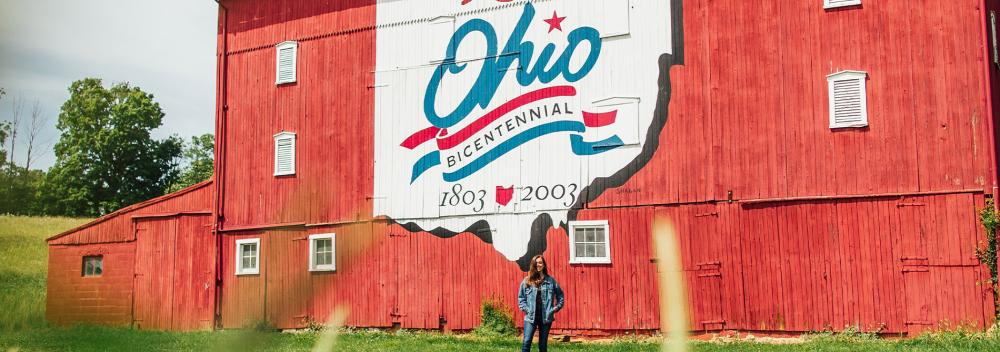 Posing with an Ohio Bicentennial mural on the side of a red barn