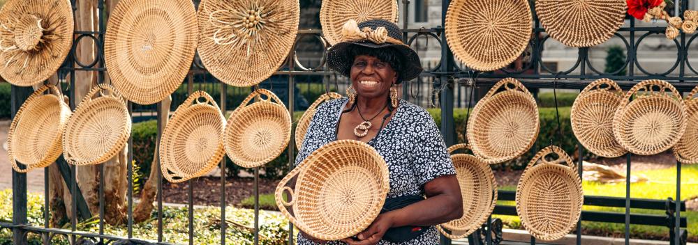 A Gullah artisan posing with one of her sweetgrass baskets in Charleston, South Carolina