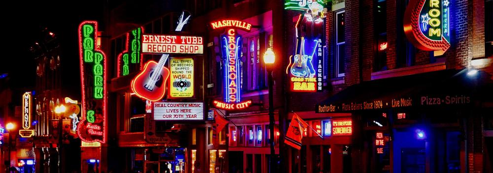 Neon lights outside live music venues illuminating Broadway in Nashville, Tennesse