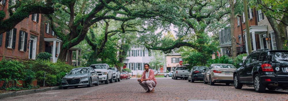 Posing on a cobblestone street lined by historic mansions and live oak trees in Savannah, Georgia